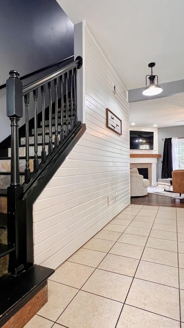2703 Westbrook Dr, Bloomington, IL 61705 - stairs with a fireplace, tile patterned floors, and wood walls
