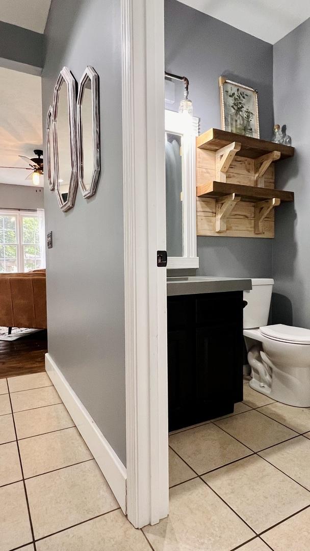 2703 Westbrook Dr, Bloomington, IL 61705 - bathroom featuring tile patterned floors, a ceiling fan, toilet, vanity, and baseboards