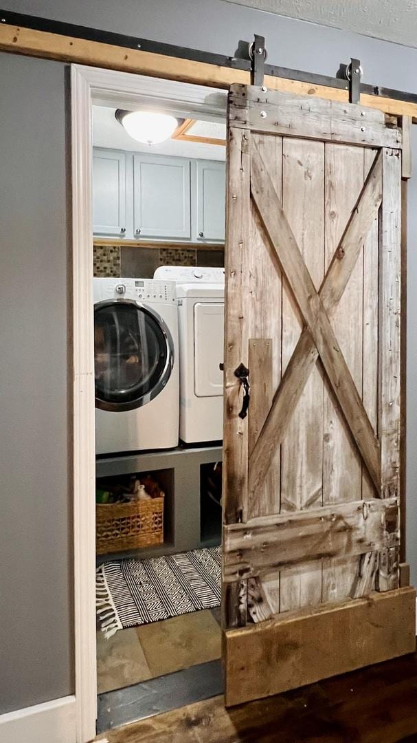 2703 Westbrook Dr, Bloomington, IL 61705 - washroom featuring cabinet space, a barn door, and washing machine and clothes dryer
