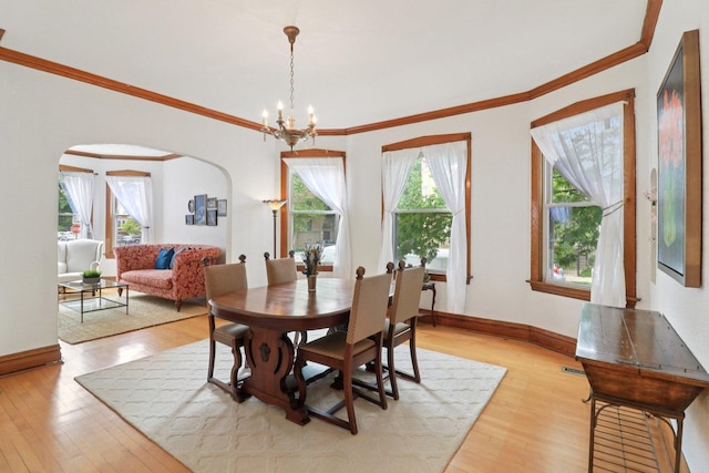 2559 N Saint Louis Ave, Chicago, IL 60647 - dining space with light wood-style floors, arched walkways, a chandelier, and ornamental molding