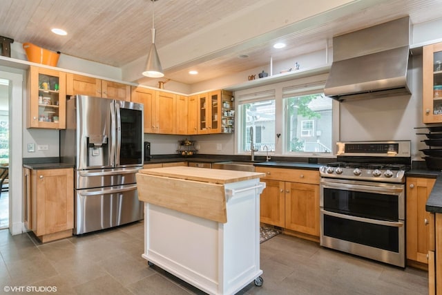 2617 Thayer St, Evanston, IL 60201 - kitchen featuring appliances with stainless steel finishes, wall chimney range hood, a center island, glass insert cabinets, and pendant lighting