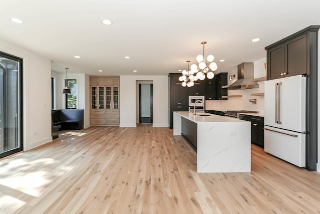26205 W Forrester Dr, Plainfield, IL 60585 - kitchen featuring wall chimney exhaust hood, freestanding refrigerator, light wood-style floors, a center island with sink, and stainless steel microwave
