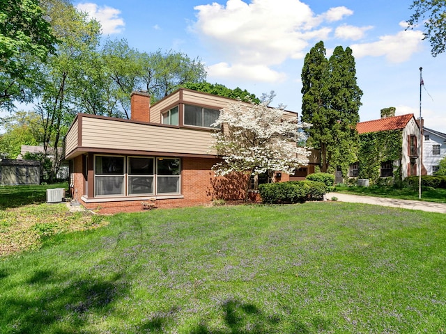 225 S Gladstone Ave, Aurora, IL 60506 - back of property with brick siding, central AC unit, a yard, and a chimney