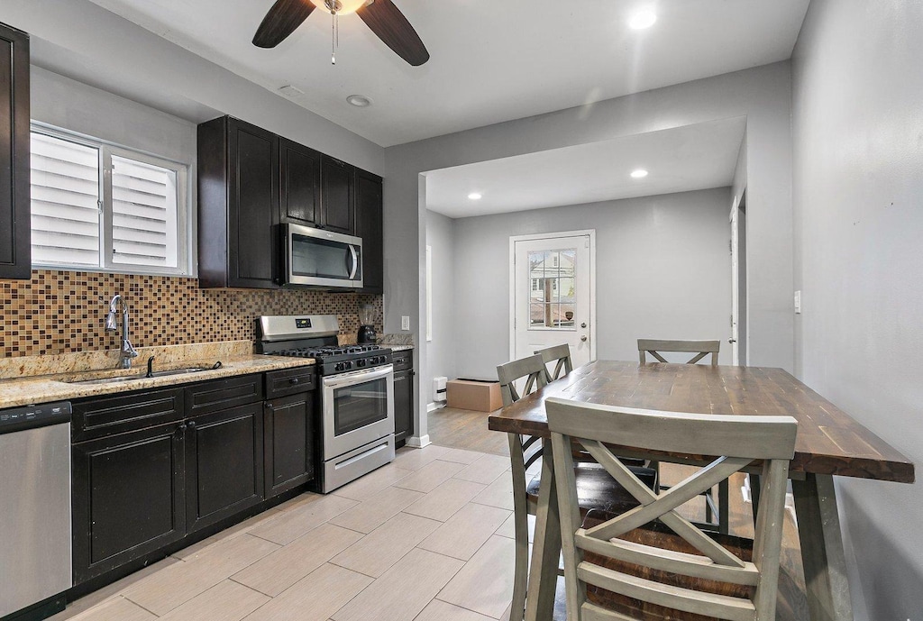 2214 N Mango Ave, Chicago, IL 60639 - kitchen featuring appliances with stainless steel finishes, a sink, dark cabinets, ceiling fan, and recessed lighting