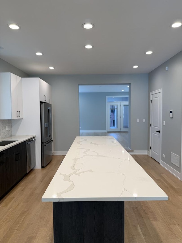 2714 W Cortez St Unit 1, Chicago, IL 60622 - kitchen with appliances with stainless steel finishes, a center island, light wood-type flooring, white cabinetry, and light stone counters
