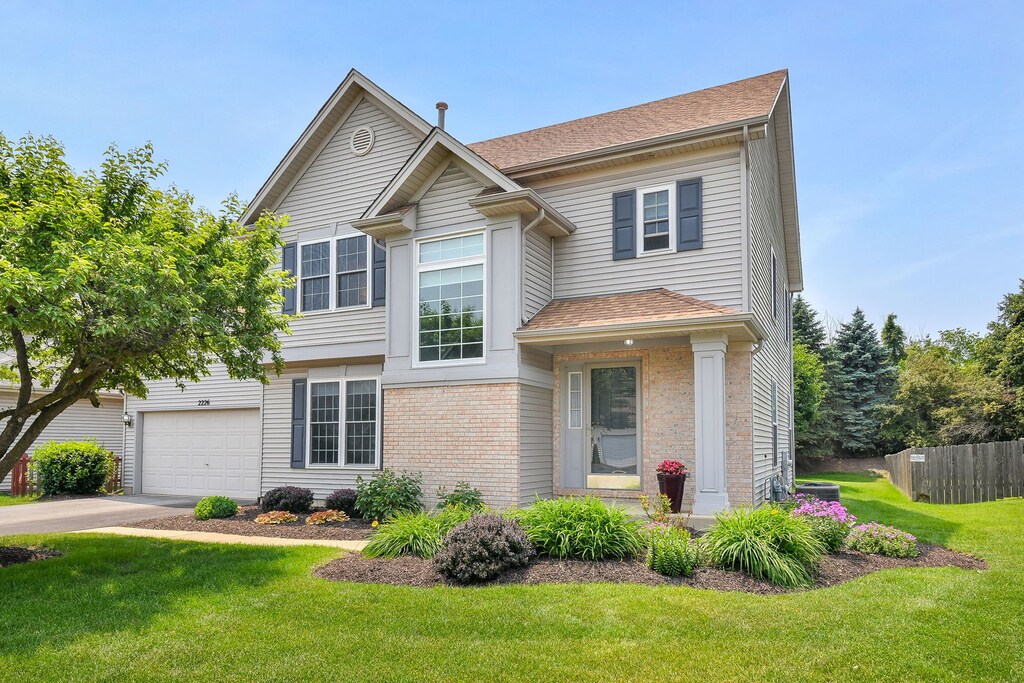 2226 Tremont Ave, Aurora, IL 60502 - view of front of house featuring brick siding, driveway, roof with shingles, and a garage