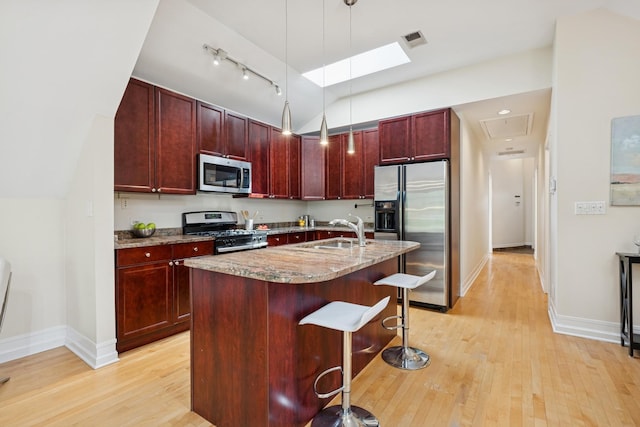 1325 W Wolfram St Unit 3, Chicago, IL 60657 - kitchen with appliances with stainless steel finishes, dark brown cabinets, light wood-type flooring, light stone countertops, and a kitchen bar