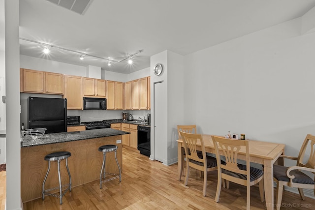 333 N Jefferson St Unit 307, Chicago, IL 60661 - kitchen with black appliances, dark countertops, a breakfast bar area, light wood-type flooring, and light brown cabinets