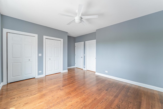 4011 W Fullerton Ave Unit 2E, Chicago, IL 60639 - unfurnished bedroom featuring two closets, baseboards, wood finished floors, and ceiling fan
