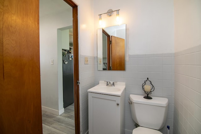 329 W Wood Ave, Peotone, IL 60468 - half bath featuring wood finished floors, vanity, toilet, tile walls, and a wainscoted wall