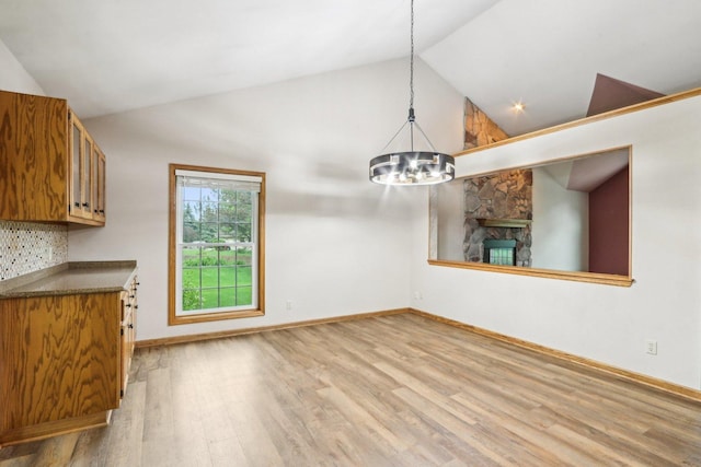 N61W14730 Woodcrest Ct, Menomonee Falls, WI 53051 - unfurnished dining area with wood finished floors, a chandelier, high vaulted ceiling, baseboards, and a stone fireplace