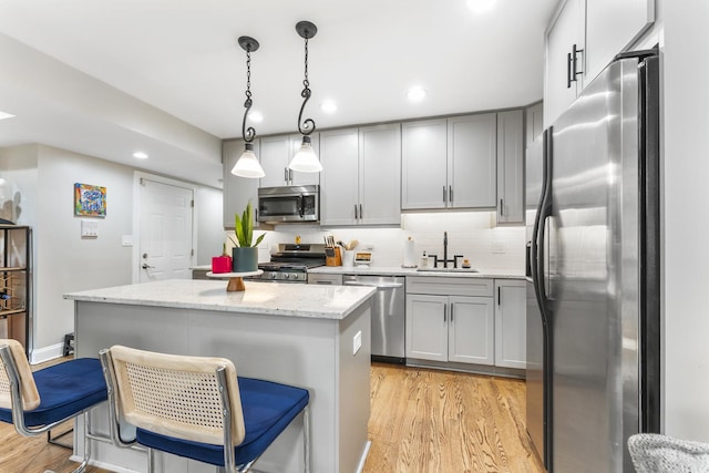 4717 N Kenmore Ave Unit Gs, Chicago, IL 60640 - kitchen with appliances with stainless steel finishes, a kitchen island, light wood-type flooring, decorative backsplash, and light stone countertops