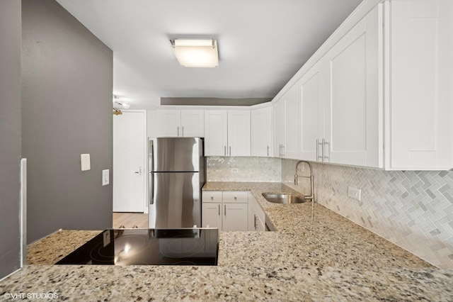 2020 N Lincoln Park W Unit 30L, Chicago, IL 60614 - kitchen with freestanding refrigerator, a sink, tasteful backsplash, and light stone counters