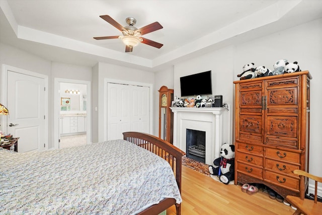 1705 N Crilly Ct Unit 2, Chicago, IL 60614 - bedroom with a tray ceiling, light wood-style flooring, a fireplace with flush hearth, a closet, and ceiling fan