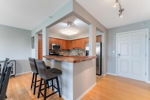 390 S Western Ave Unit 504, Des Plaines, IL 60016 - kitchen featuring stainless steel appliances, light wood-style flooring, decorative backsplash, and a kitchen bar