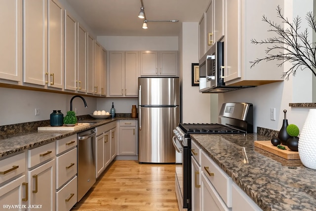 330 N Clinton St Unit 303, Chicago, IL 60661 - kitchen featuring stainless steel appliances, light wood-type flooring, dark stone countertops, and a sink