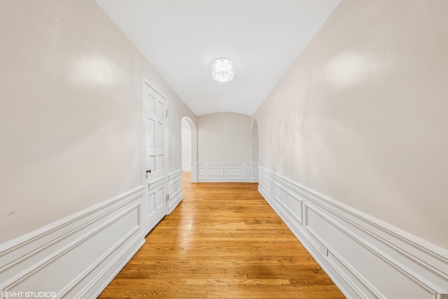 6901 S Oglesby Ave Unit 2A, Chicago, IL 60649 - hall featuring a decorative wall, arched walkways, a wainscoted wall, and light wood-style flooring