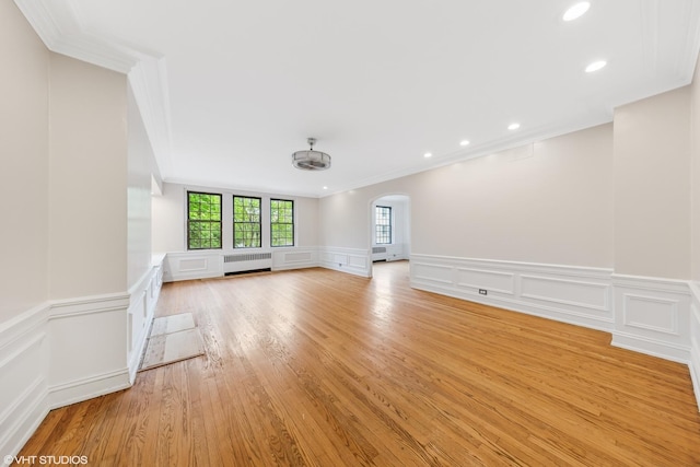 6901 S Oglesby Ave Unit 2A, Chicago, IL 60649 - unfurnished living room featuring radiator, crown molding, arched walkways, a decorative wall, and wainscoting