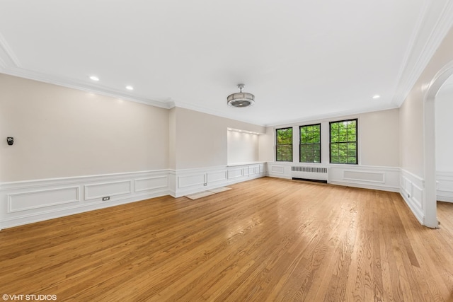 6901 S Oglesby Ave Unit 2A, Chicago, IL 60649 - empty room featuring radiator, crown molding, arched walkways, a decorative wall, and light wood-style flooring