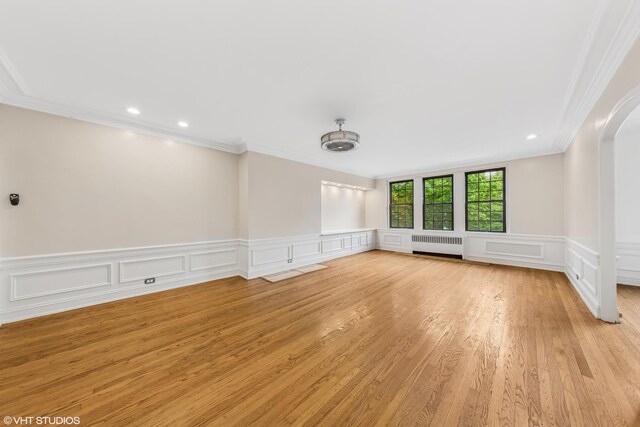 6901 S Oglesby Ave Unit 2A, Chicago, IL 60649 - empty room featuring radiator, crown molding, arched walkways, a decorative wall, and light wood-style flooring