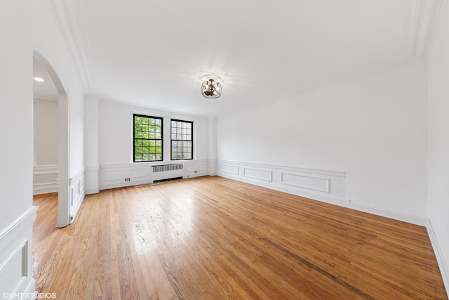 6901 S Oglesby Ave Unit 2A, Chicago, IL 60649 - unfurnished room with radiator, arched walkways, crown molding, a decorative wall, and light wood-style floors