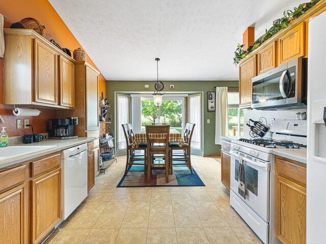 4306 Westridge Dr, Winnebago, IL 61088 - kitchen featuring white appliances, light countertops, a textured ceiling, a sink, and pendant lighting