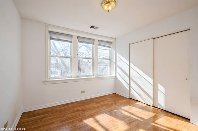 238 W 31st St Unit 2W, Chicago, IL 60616 - unfurnished bedroom featuring multiple windows, wood finished floors, a closet, and baseboards