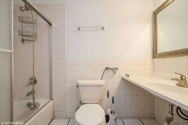 238 W 31st St Unit 2W, Chicago, IL 60616 - bathroom featuring tile walls, toilet, a sink, bathing tub / shower combination, and wainscoting