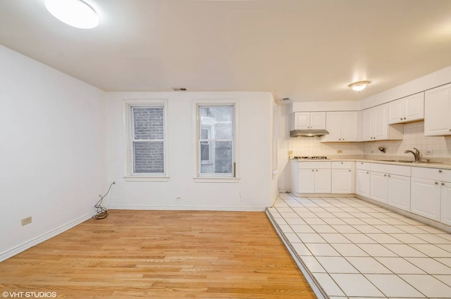238 W 31st St Unit 2W, Chicago, IL 60616 - kitchen with a sink, light wood finished floors, tasteful backsplash, under cabinet range hood, and white cabinetry
