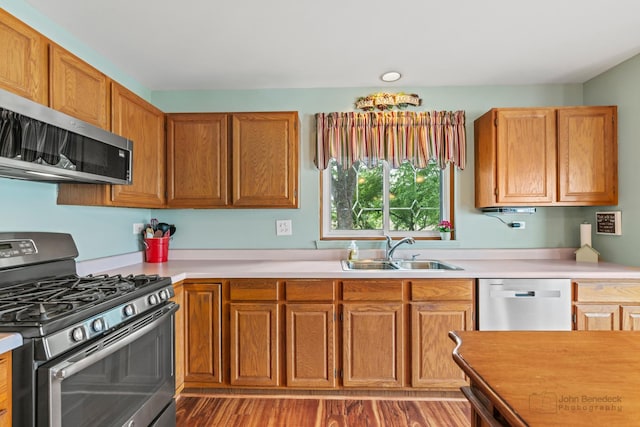 7 Farmington Ct, Lake In The Hills, IL 60156 - kitchen featuring appliances with stainless steel finishes, a sink, light countertops, brown cabinets, and light wood finished floors