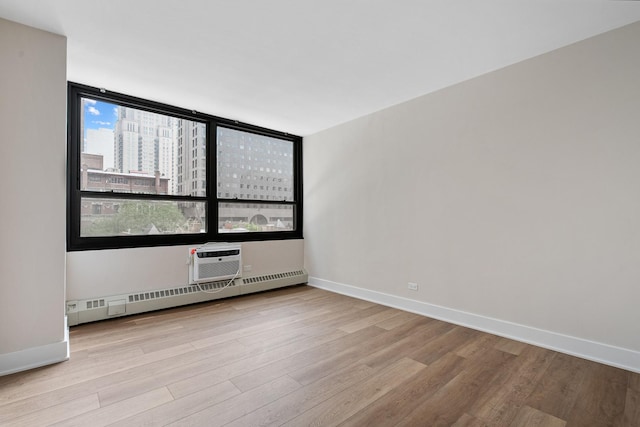 33 E Cedar St Unit 6B, Chicago, IL 60611 - empty room featuring baseboard heating, wood finished floors, baseboards, a wall mounted air conditioner, and a city view