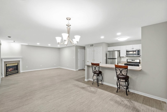 9810 Parkway Dr None, Unit None, Highland, IN 46322 - kitchen with stainless steel appliances, white cabinetry, light countertops, a kitchen bar, and a peninsula