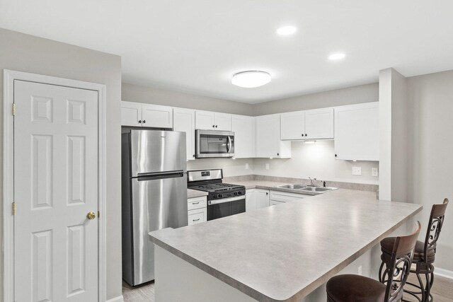 9810 Parkway Dr None, Unit None, Highland, IN 46322 - kitchen featuring stainless steel appliances, a sink, a peninsula, a kitchen bar, and baseboards