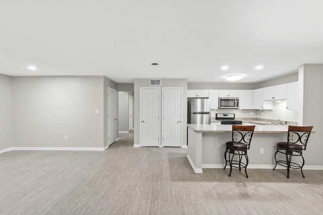 9810 Parkway Dr None, Unit None, Highland, IN 46322 - kitchen with stainless steel appliances, baseboards, light countertops, a peninsula, and a kitchen bar