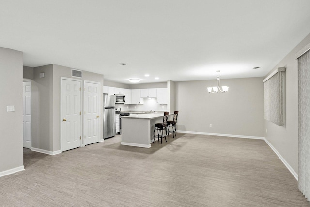 9810 Parkway Dr None, Unit None, Highland, IN 46322 - kitchen featuring appliances with stainless steel finishes, a chandelier, white cabinetry, a kitchen bar, and baseboards