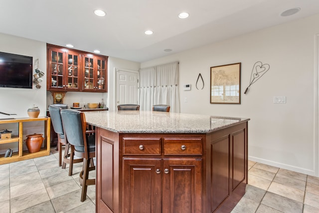 2910 Greystone Pl, Champaign, IL 61822 - kitchen featuring recessed lighting, a center island, light tile patterned floors, light stone countertops, and glass insert cabinets