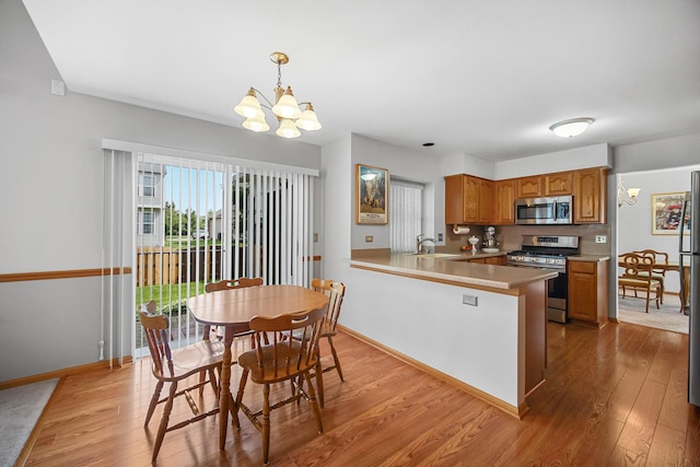 2802 Forestview Dr, Carpentersville, IL 60110 - kitchen with appliances with stainless steel finishes, light wood-style floors, a chandelier, and brown cabinetry