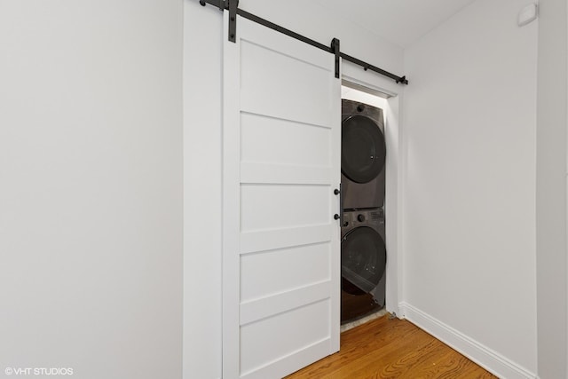 1114 W Pratt Blvd Unit 3S, Chicago, IL 60626 - washroom with a barn door, stacked washing machine and dryer, and light wood-type flooring