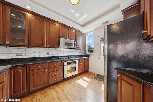 1114 W Pratt Blvd Unit 3S, Chicago, IL 60626 - kitchen featuring stainless steel appliances, light wood-style flooring, tasteful backsplash, dark countertops, and glass insert cabinets