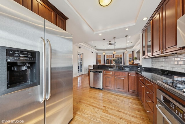 1114 W Pratt Blvd Unit 3S, Chicago, IL 60626 - kitchen featuring appliances with stainless steel finishes, a tray ceiling, a peninsula, crown molding, and light wood-style flooring