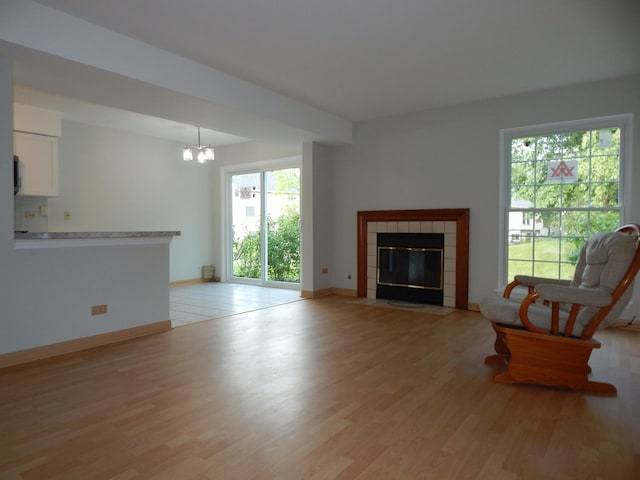 1 N Oltendorf Rd, Streamwood, IL 60107 - living area with light wood finished floors, a tiled fireplace, a chandelier, and baseboards