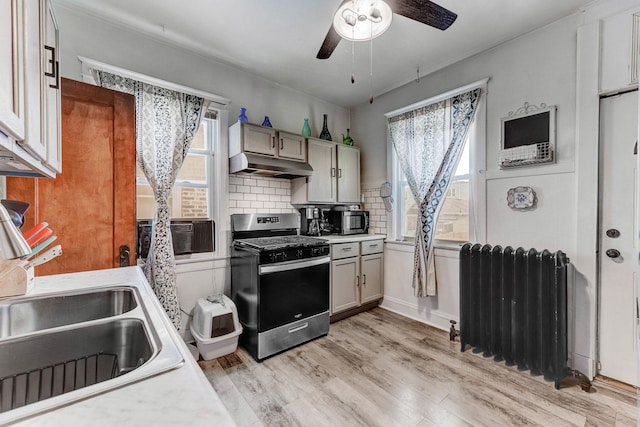 6142 S Richmond St, Chicago, IL 60629 - kitchen featuring stainless steel range with gas cooktop, radiator heating unit, under cabinet range hood, a ceiling fan, and a sink