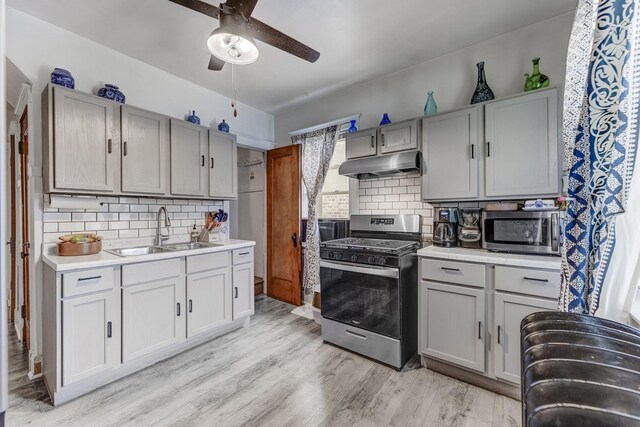 6142 S Richmond St, Chicago, IL 60629 - kitchen with appliances with stainless steel finishes, under cabinet range hood, a sink, a ceiling fan, and tasteful backsplash