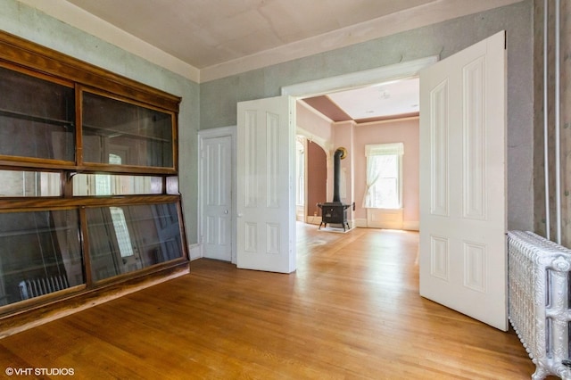 100 E Miller Ave, Hinckley, IL 60520 - spare room featuring radiator, light wood finished floors, arched walkways, and a wood stove