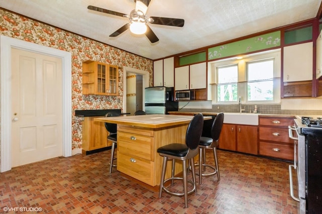 100 E Miller Ave, Hinckley, IL 60520 - kitchen with stainless steel appliances, wallpapered walls, a ceiling fan, backsplash, and a breakfast bar area