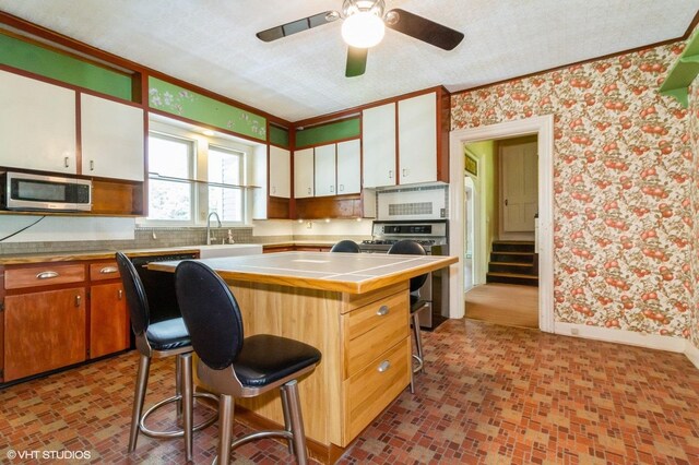 100 E Miller Ave, Hinckley, IL 60520 - kitchen with appliances with stainless steel finishes, tile countertops, wallpapered walls, white cabinetry, and ceiling fan