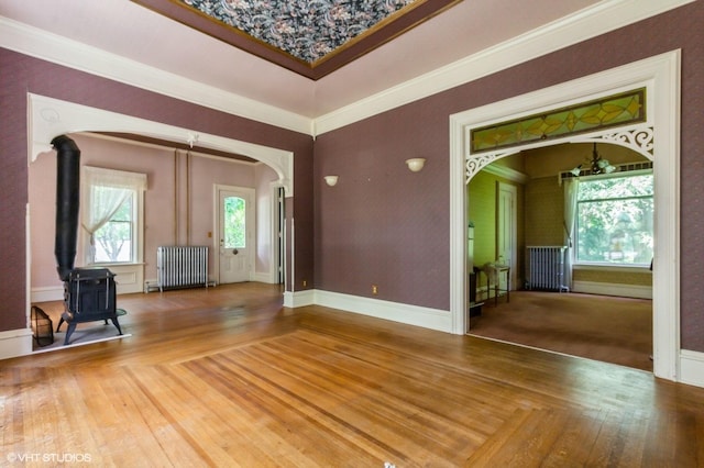 100 E Miller Ave, Hinckley, IL 60520 - spare room featuring radiator, arched walkways, a wood stove, wood-type flooring, and crown molding