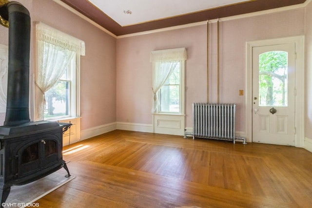 100 E Miller Ave, Hinckley, IL 60520 - unfurnished living room with radiator, a wood stove, healthy amount of natural light, and wood finished floors