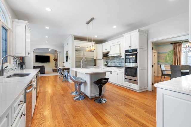 1455 Littlefield Ct, Lake Forest, IL 60045 - kitchen featuring a sink, appliances with stainless steel finishes, arched walkways, tasteful backsplash, and a breakfast bar