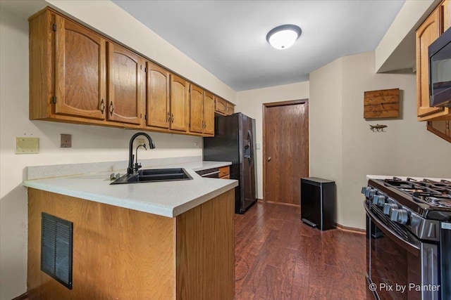 2116 Glasgow Ct, Hanover Park, IL 60133 - kitchen featuring black appliances, light countertops, brown cabinetry, dark wood finished floors, and a peninsula